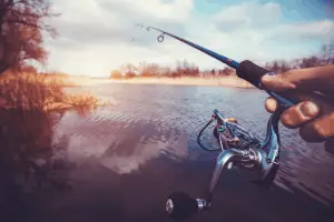Hand with vr spinning reel on the evening summer lake