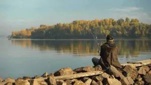 Professional fisherman fishing on river bank with rod and reel