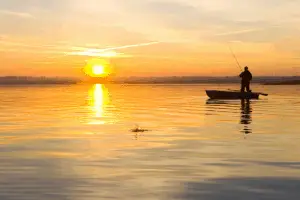 Fisherman fishing with sun in the background