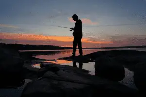 silhouette of a man fishing at sunset