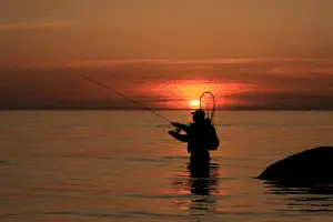 fisherman catching fish at sunset in the lake