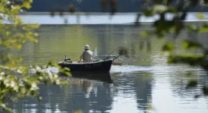 man fishing from a boat in the middle of the lake