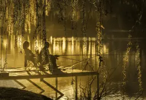 two anglers fishing on the lake at sunset