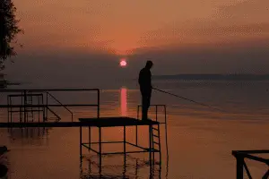 angler fishing in a lake at sunset