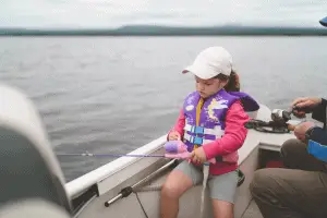 young girl fishing from a boat in the middle of the lake