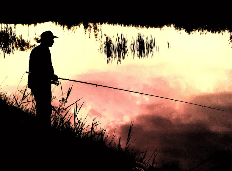 angler fishing against a sunset reflection