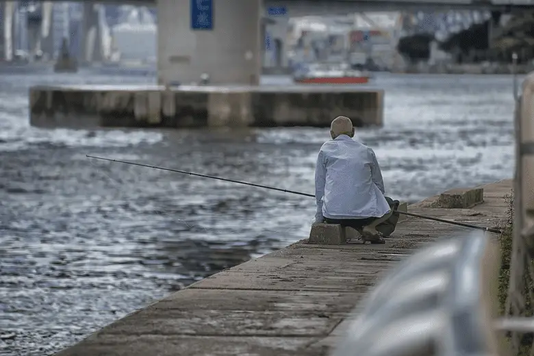 hombre pescando desde el muelle de la ciudad