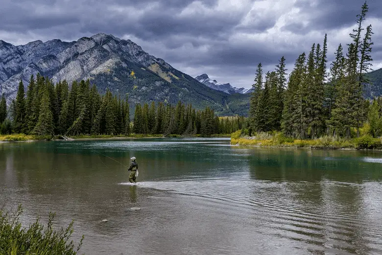 angler fishing in a river near the mountain