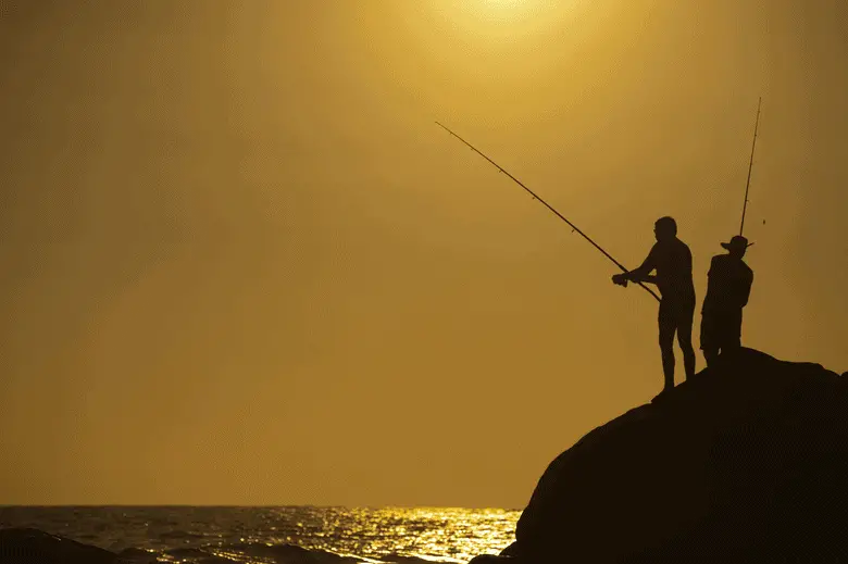 siluetas de dos pescadores pescando al atardecer