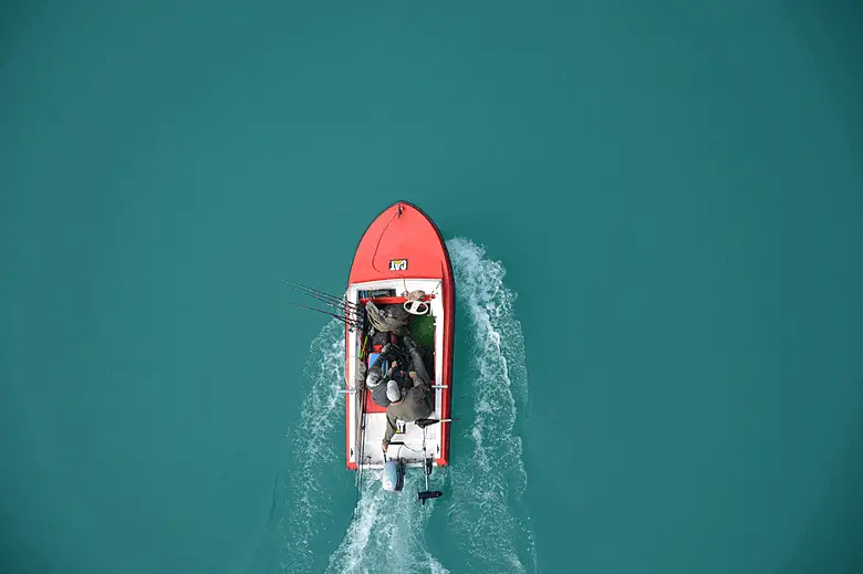 bird eye view of a fishing boat going through blue lake