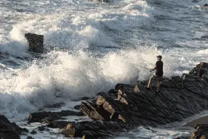 angler fishing from the shore against high waves