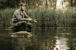 angler sitting on a rock in the river fishing