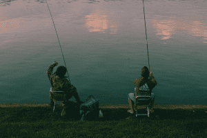 two angler sitting on chairs and fishing at the lake