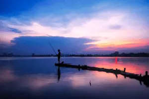 silhouette of angler fishing at sunset