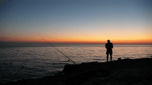 angler fishing at sunset